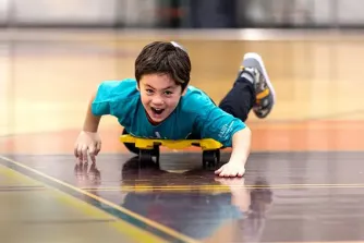 Summer camper riding scooter at Rush Copley Healthplex