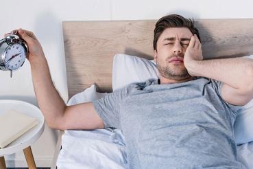 Man waking to alarm clock