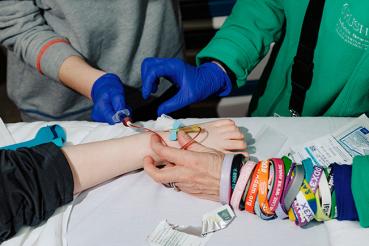 photograph showing the arms of two people administering an infusion to someone