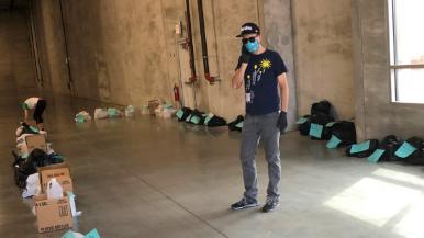 A man wearing a surgical mask with bags and boxes of supplies